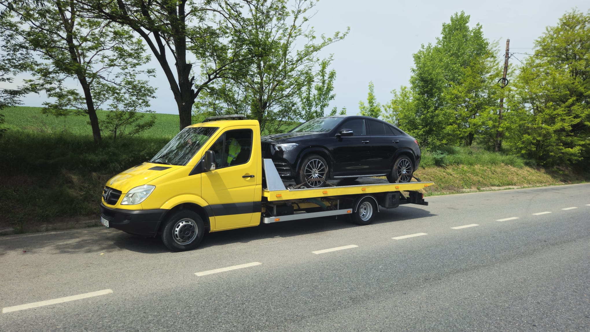 SUV Mercedes GLE Coupe incarcat pe platforma galbena Traian TKD, in afara orasului Iasi, pregatit pentru transport.