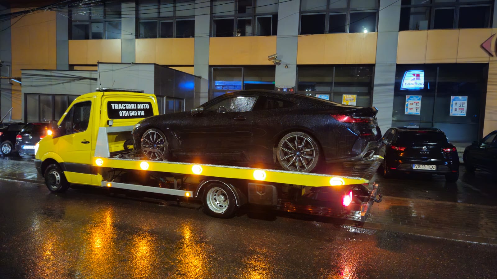 BMW nou, coupe sport, tractat pe platforma Traian TKD noaptea, cu luminile platformei aprinse.