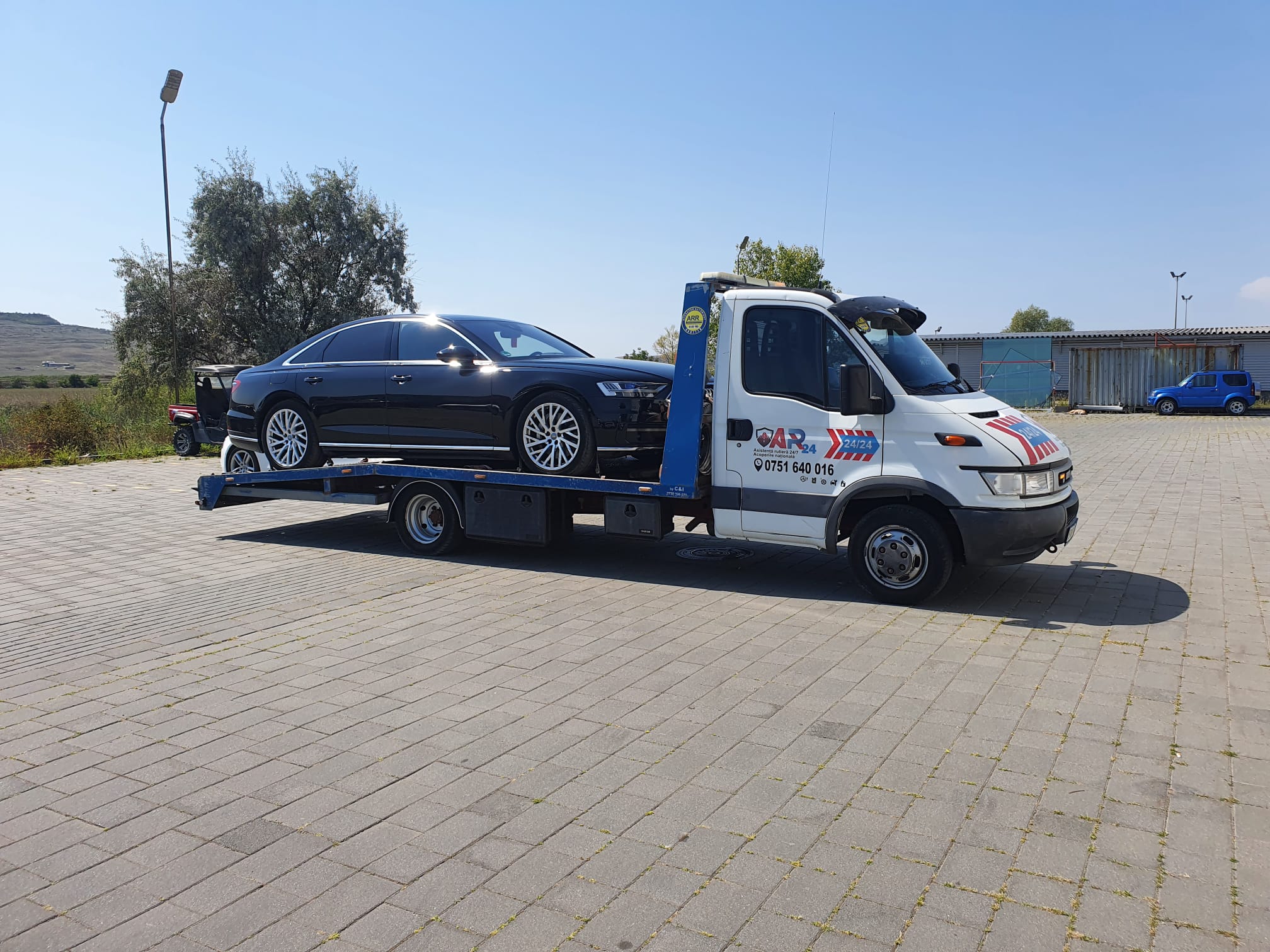 Audi A6 lung, de lux, incarcat pe platforma auto Traian TKD intr-o parcare. Servicii de tractari auto non stop disponibile si in Targu Frumos