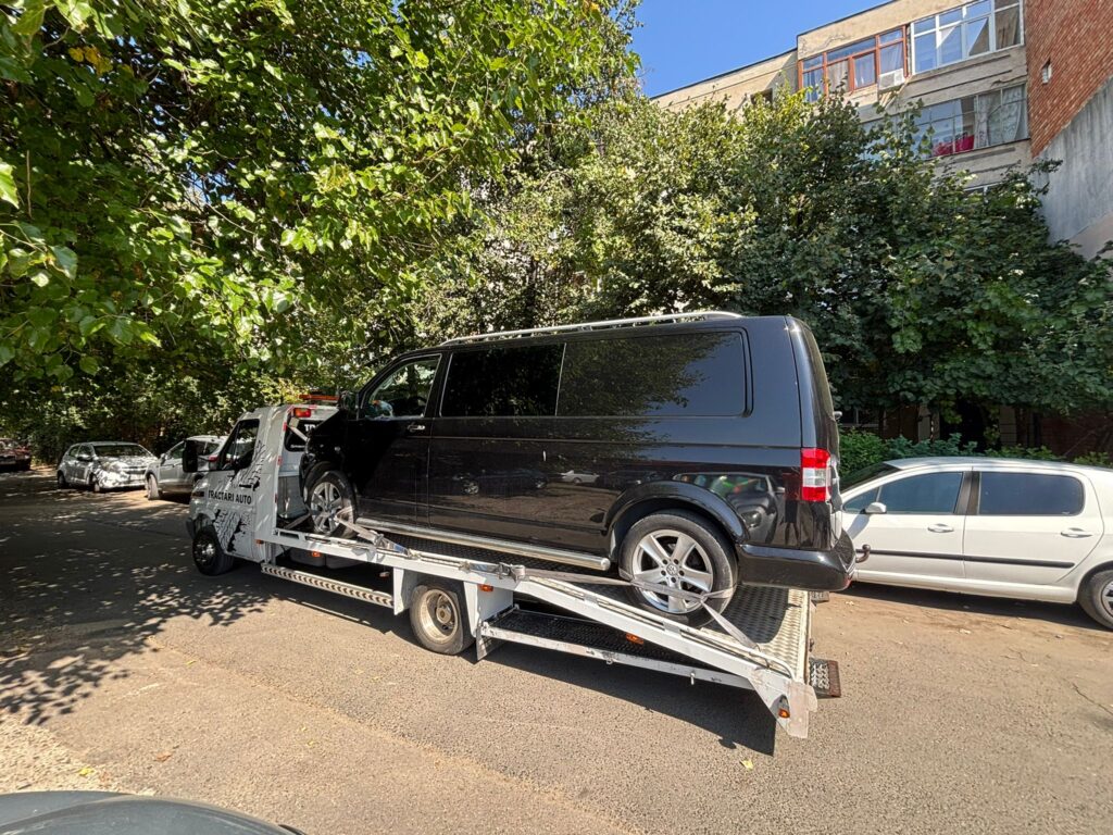 Autospecială de tractări Traian TKD transportând un van Volkswagen pe o stradă din Iași, un exemplu al serviciului nostru de platforma auto Iași preț competitiv și sigur.