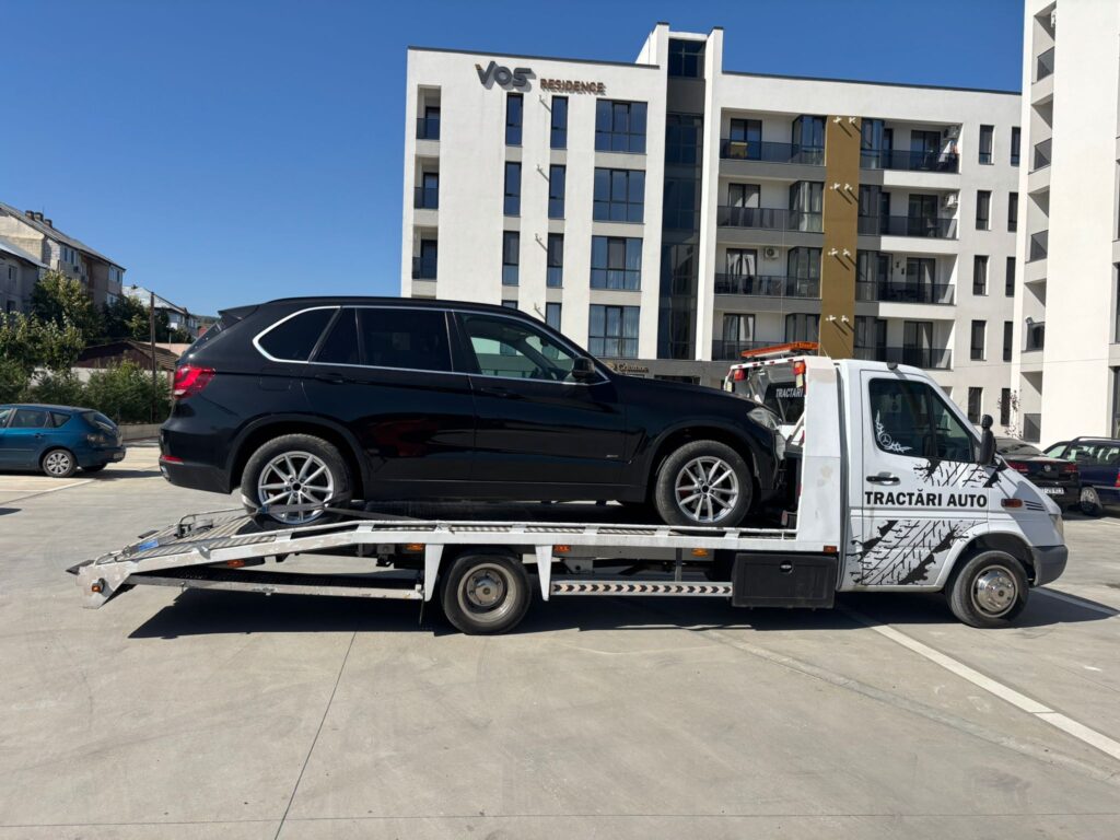 Platformă Traian TKD transportând un SUV BMW X5, un exemplu de servicii profesioniste de tractări auto Iași la un preț corect.