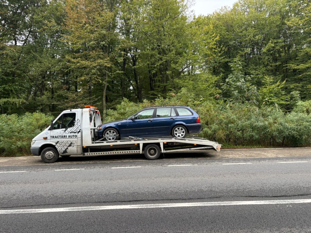 Autospecială Traian TKD în timpul unei operațiuni de remorcare auto iasi, transportând în siguranță un BMW Seria 3 albastru pe platformă.