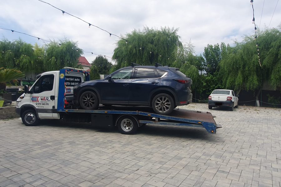 Un autoturism Mazda SUV de culoare închisă, încărcat pe platforma auto în Iasi a firmei Traian TKD, pregătit pentru transport rapid și sigur pe drumurile din Iași.