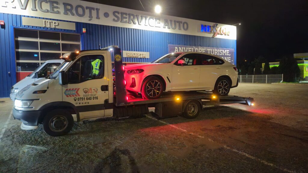 SUV alb BMW incarcat pe platforma in fata unui service auto din Nicolina, Iasi
